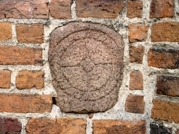 Symbol wykuty w kamieniu wmurowanym w cian wiey kocioa farnego.<br>Prawdopodobnie  przedchrze­cijaski  symbol solarny.