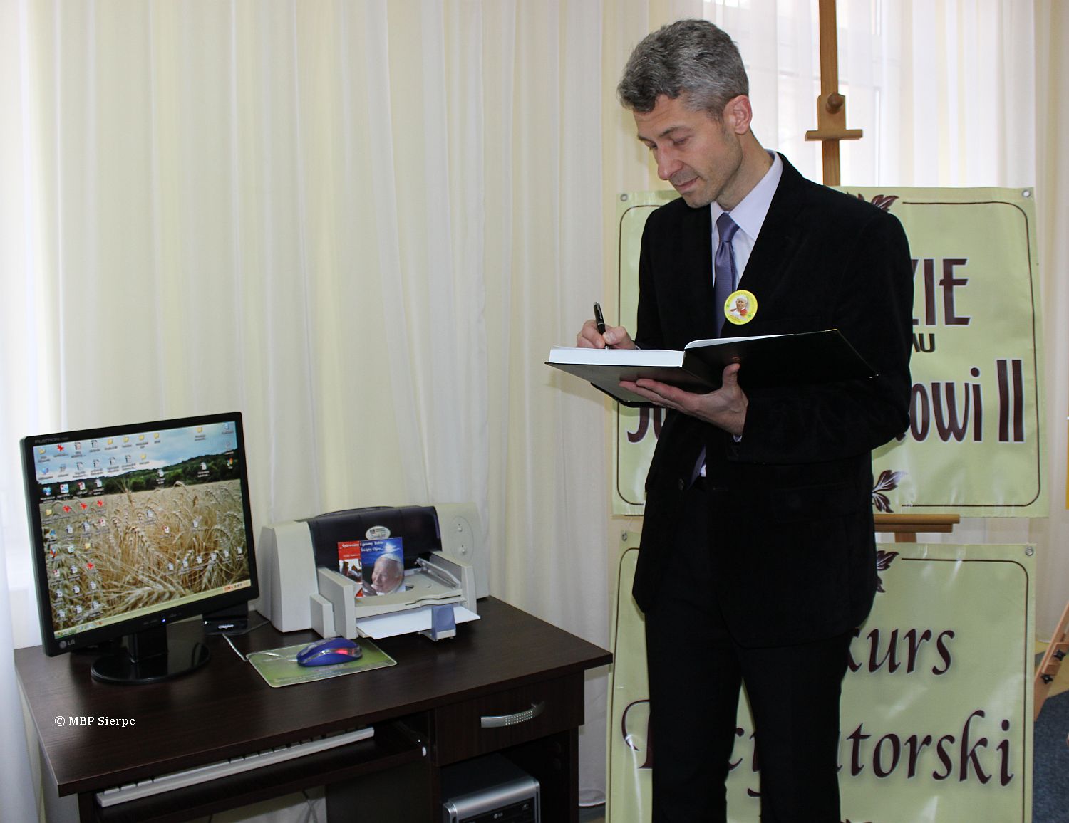 Marek Zdrojewski, inspektor Wydziau Owiaty, Kultury i Zdrowia, dokonuje pamitkowego wpisu do Kroniki wystawy 