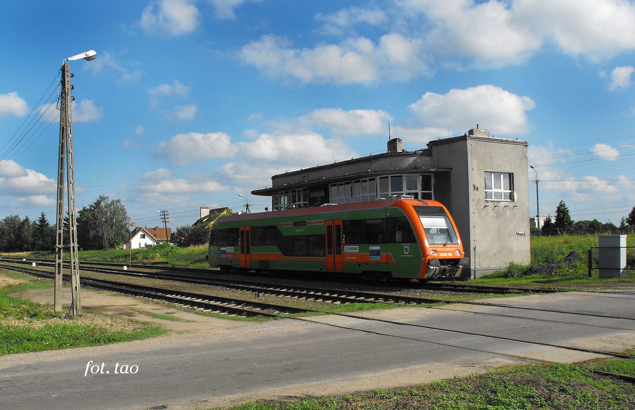 Przejazd kolejowy na ul. Dworcowej. Ten dziwny budynek PKP to nastawnia wykonawcza, a przed ni mkncy szynobus do Torunia, 8.07.2012 r.