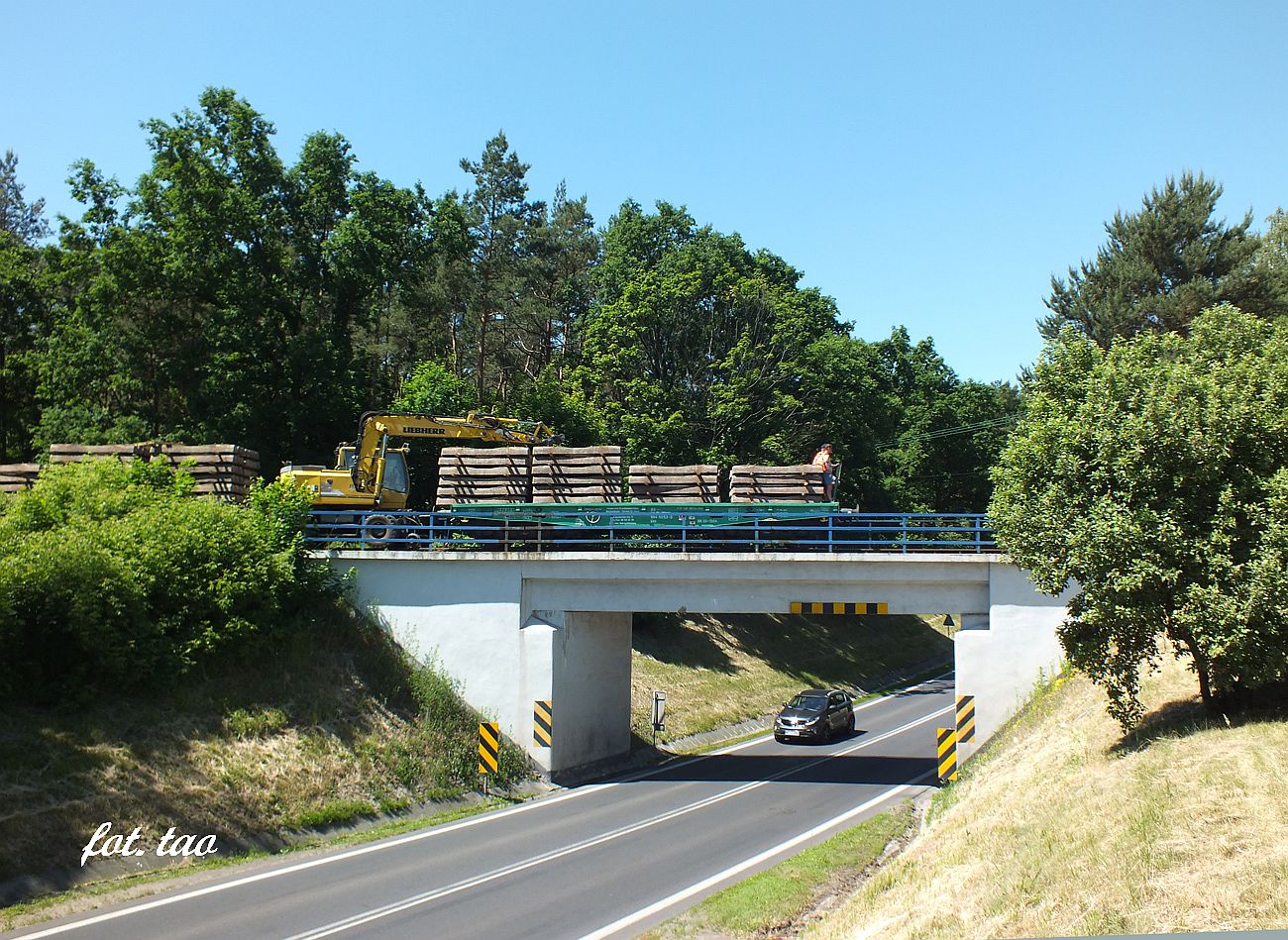 Jako lokomotywy uywa si specjalnie przygotowanej koparki, ktra posiada koa toczne torowe, a napdza si tradycyjnie przez koa gumowe przylegajce do szyn. Na fotografii transport podkadw pokonuje wiadukt nad tras DK 10 16.06.2021 r.