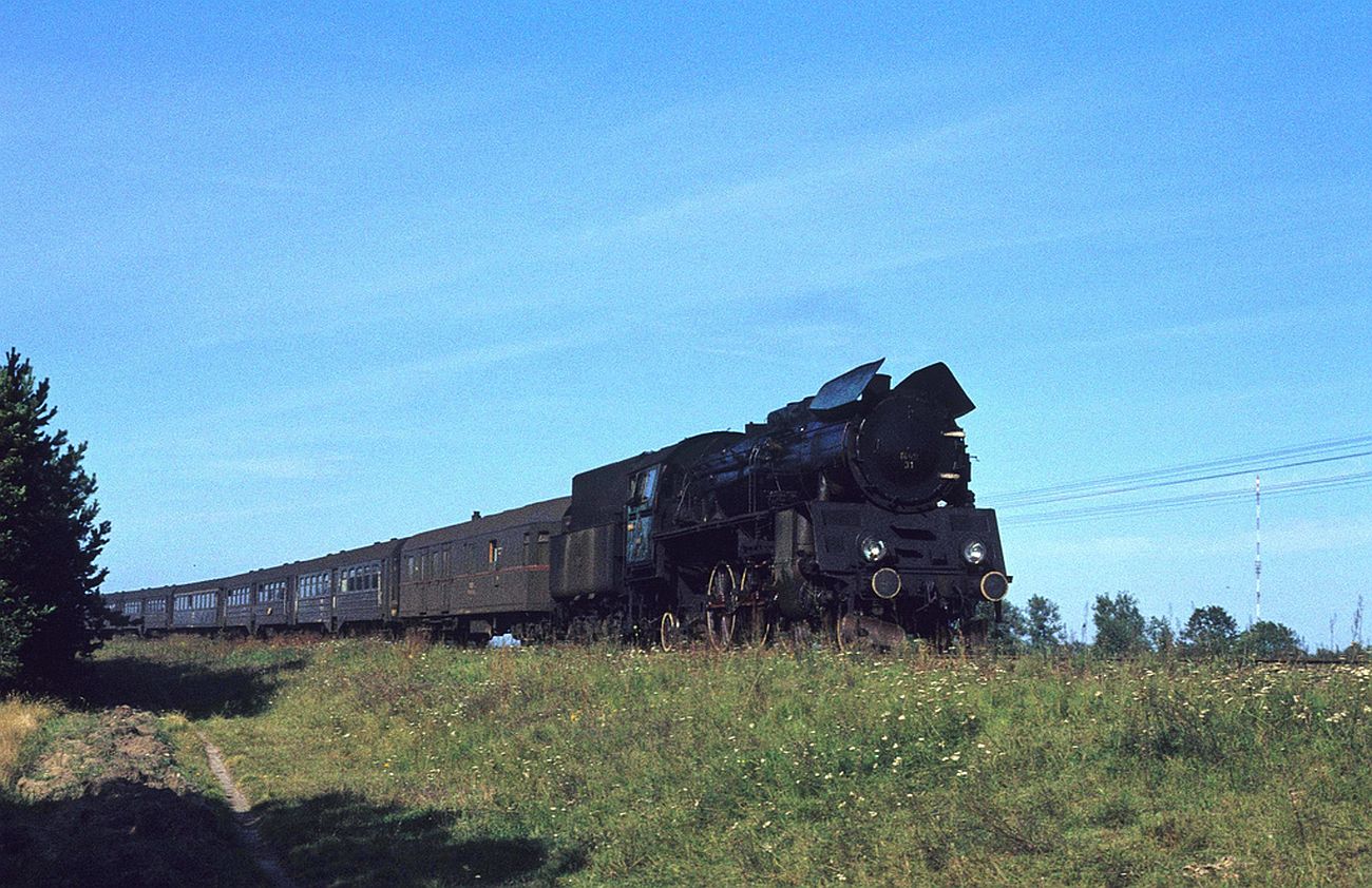 Sierpecka zaoga w parowozie Ol49 wraca z Brodnicy. W oddali wida maszt radiowy w Rachocinie. Za chwil pocig minie wiadukt nad tras nr 10 W-wa-Toru i most na Skrwie k/skansenu. Foto z 1980 r.(opis tao).